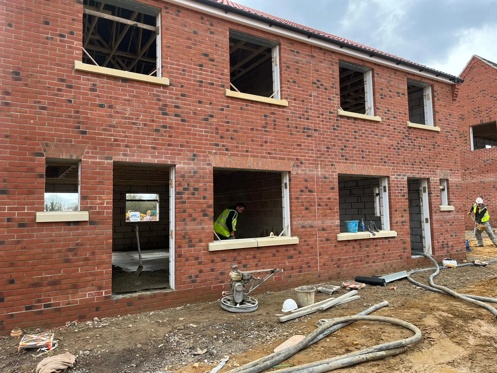 New-build houses under construction with red brickwork and cast-stone lintels, by Cambourne Brickwork & Building